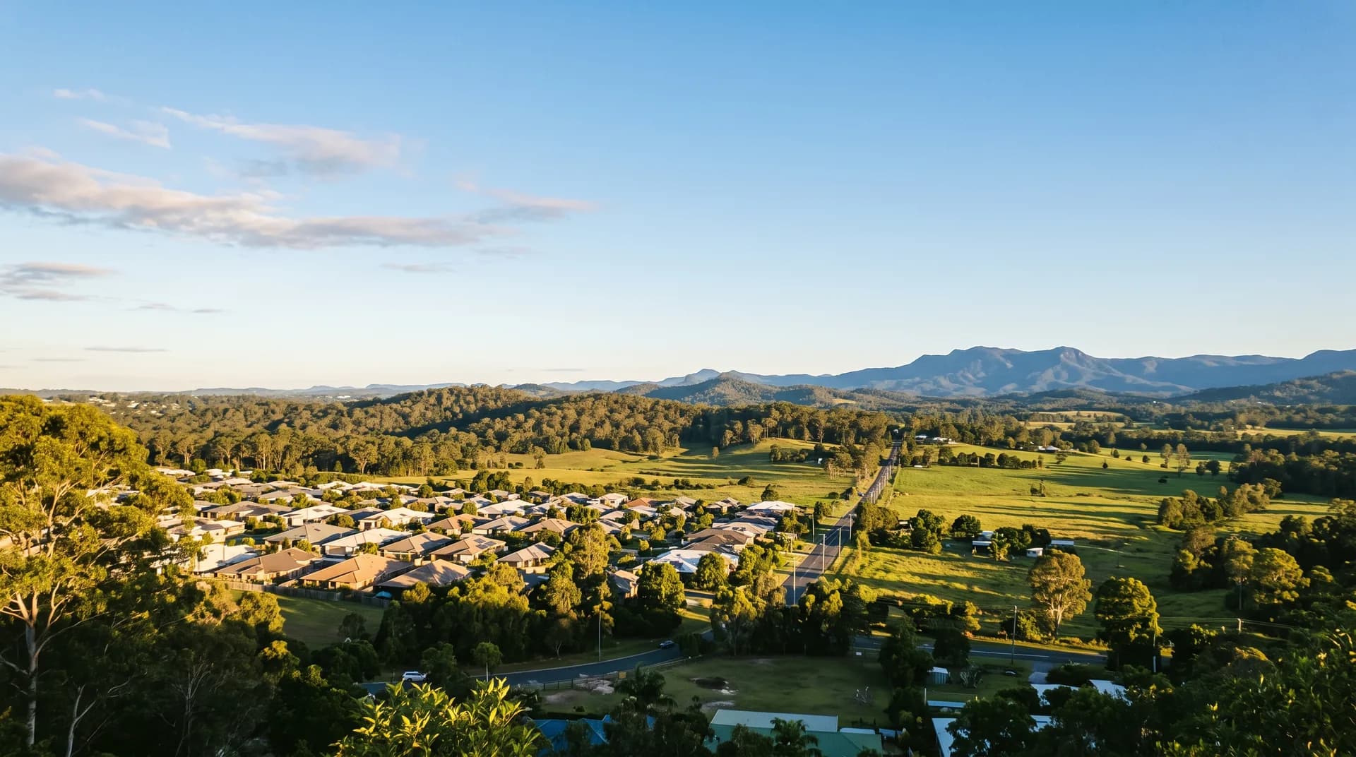 The North Brisbane service area landscape in warm afternoon sunlight, from suburb to hinterland