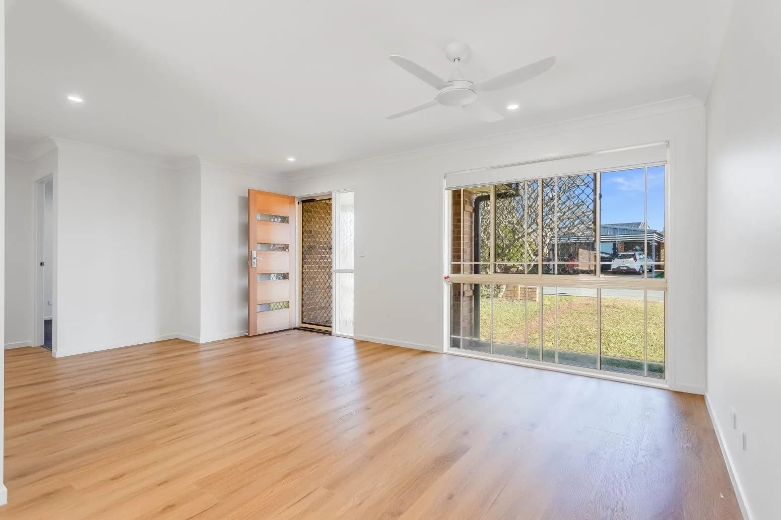 Todd's renovated open-plan living room with new timber-look flooring, fresh white walls and a large picture window